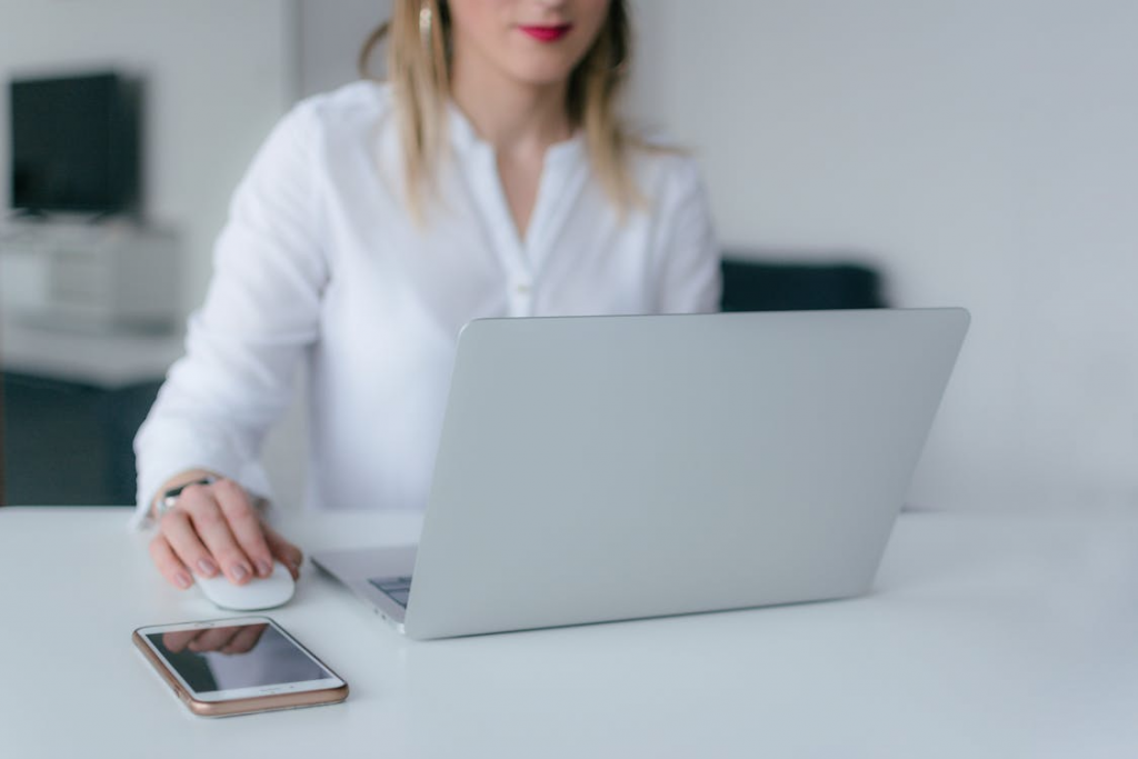 a woman in a white blouse using her computer.