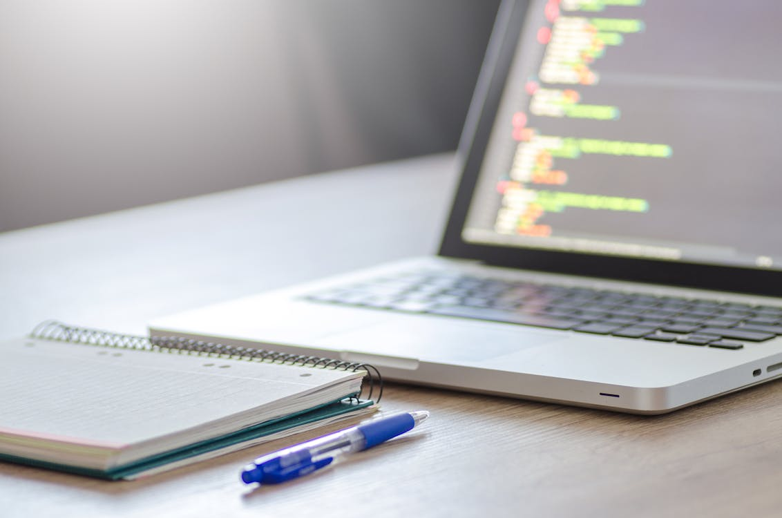 a notebook and a laptop on a desk.